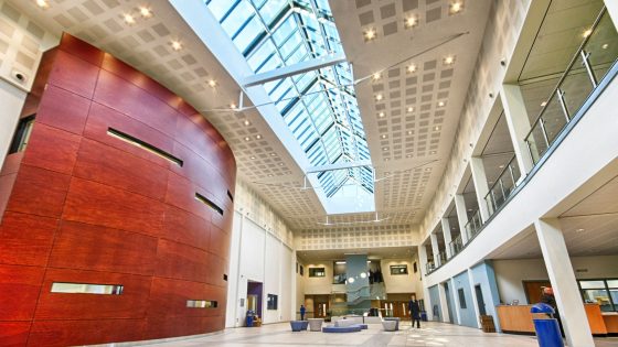 Inside of a bright, airy and open plan office building. Featuring a prominent red wall partition to the left.